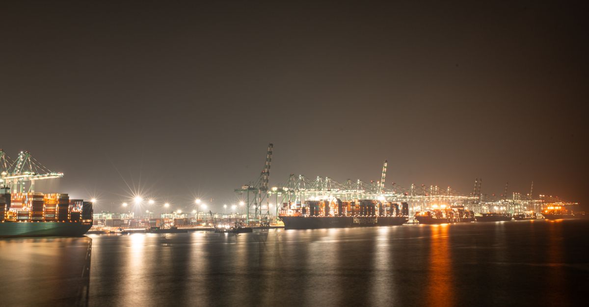 Luminous night view of a bustling industrial port with cargo ships.